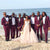 grooms wearing burgundy tuxedo with groomsmen with bride