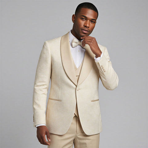 Man wearing a ivory pattern tuxedo with a bow tie against a gray background