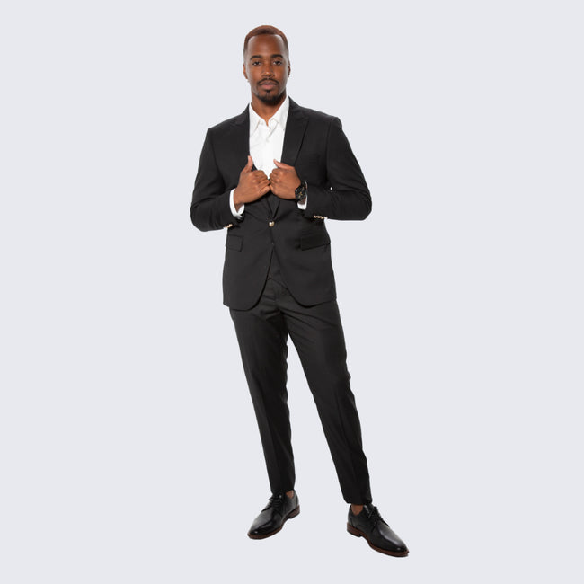 man wearing black three piece suit with gold buttons at wedding