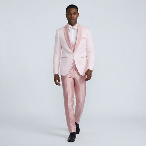 Man wearing a light pink tuxedo with a white shirt on a plain background