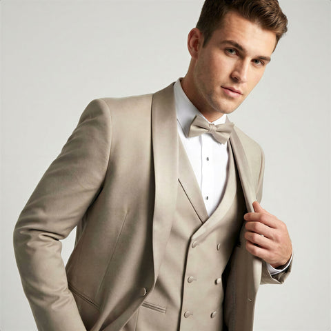 Man wearing a champagne shawl tuxedo with a white shirt and bow tie on a light gray background